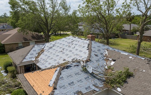 Residential roof in Lafayette with missing shingles and exposed underlayment after strong winds