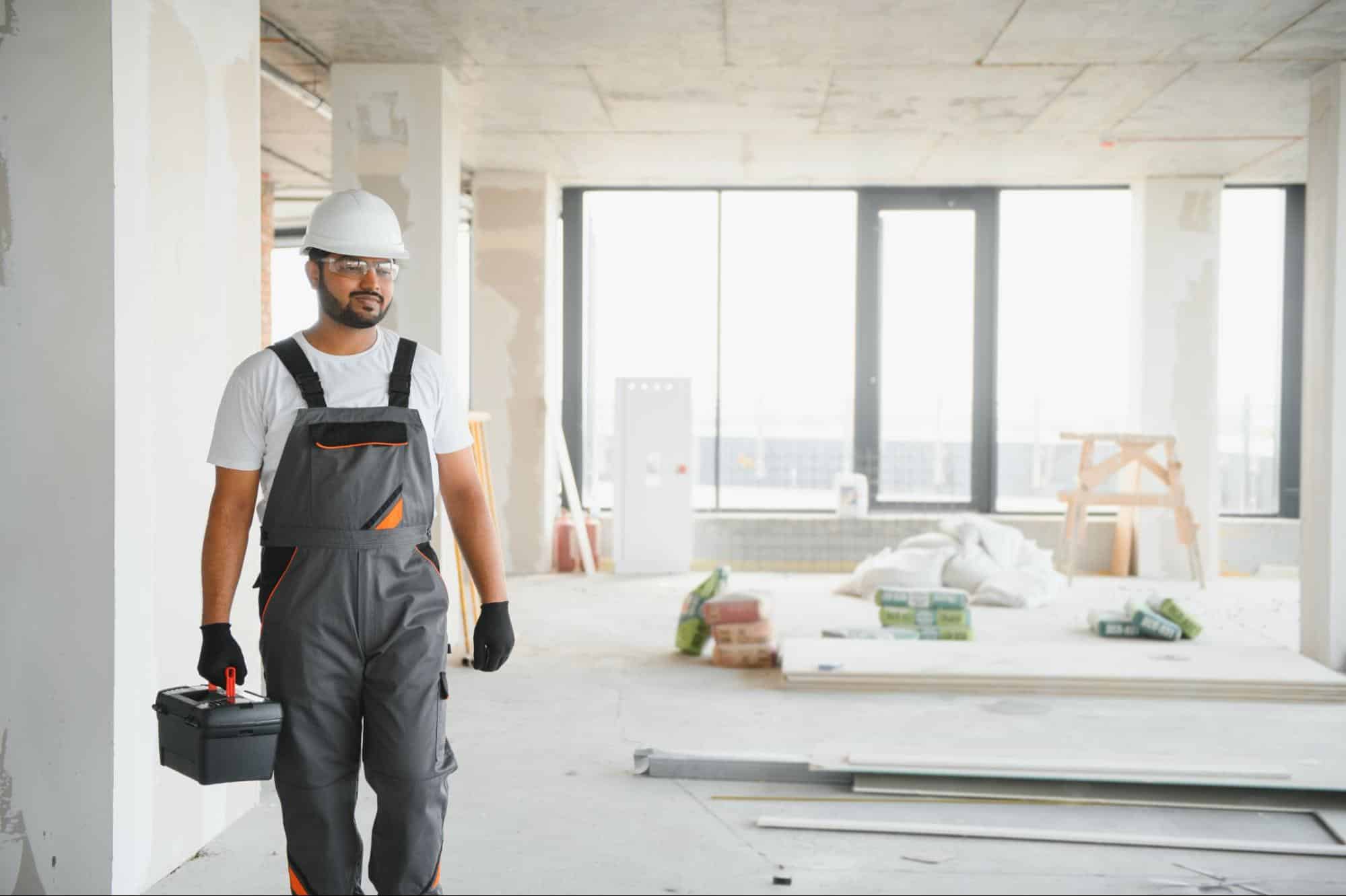 worker makes repairs in an apartment, symbolizing the services provided by Dallas TX general contractors.