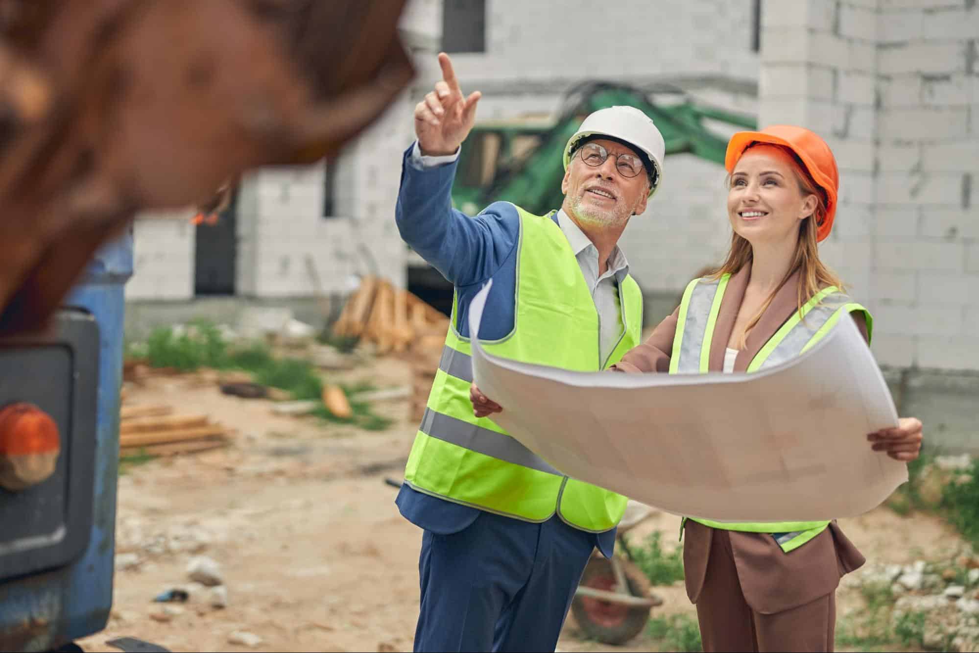 general contractor reviewing blueprints with a colleague on a construction site, representing planning and project coordination.