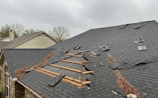 residential roof in Lafayette with missing shingles and exposed underlayment after strong winds, requiring help from Lafayette LA Wind Damage Repair expert
