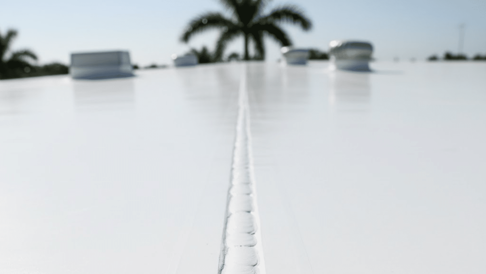 white TPO commercial roof surface with a focus on a section of crisp, heat-welded seams of the single-ply membrane