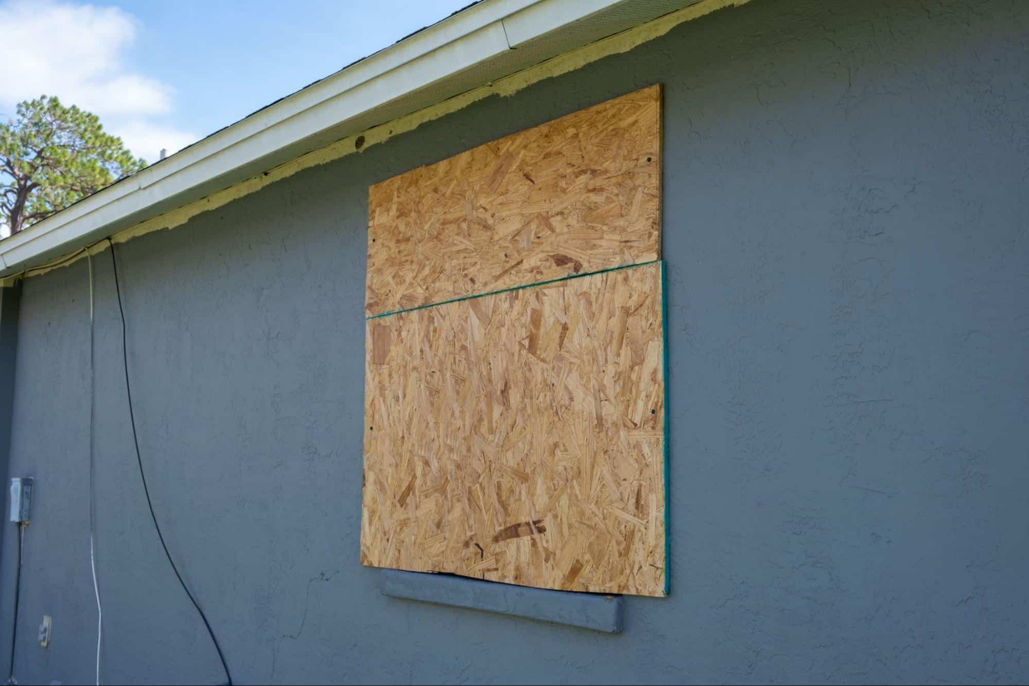 Hurricane shutters made from plywood mounted for protection of house windows.