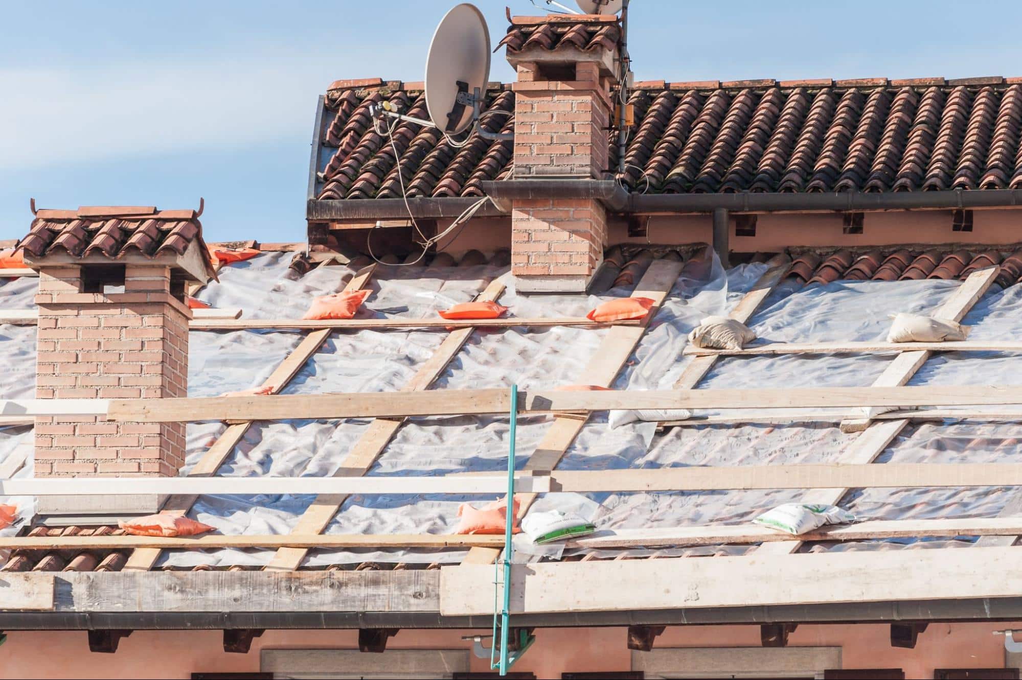 storm-damaged roof under repair, showing the work of restoration contractors
