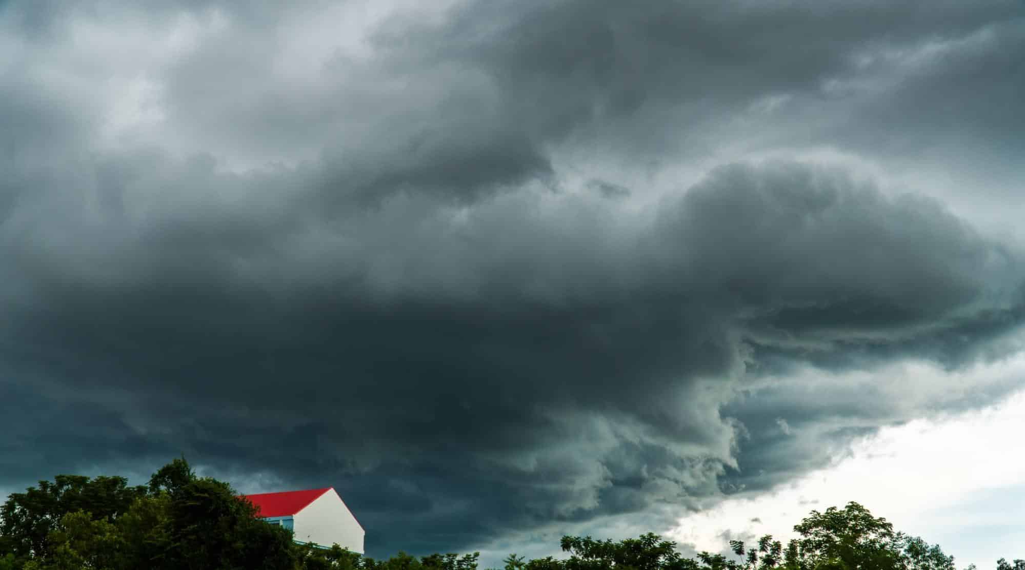 house with red roof under storm clouds