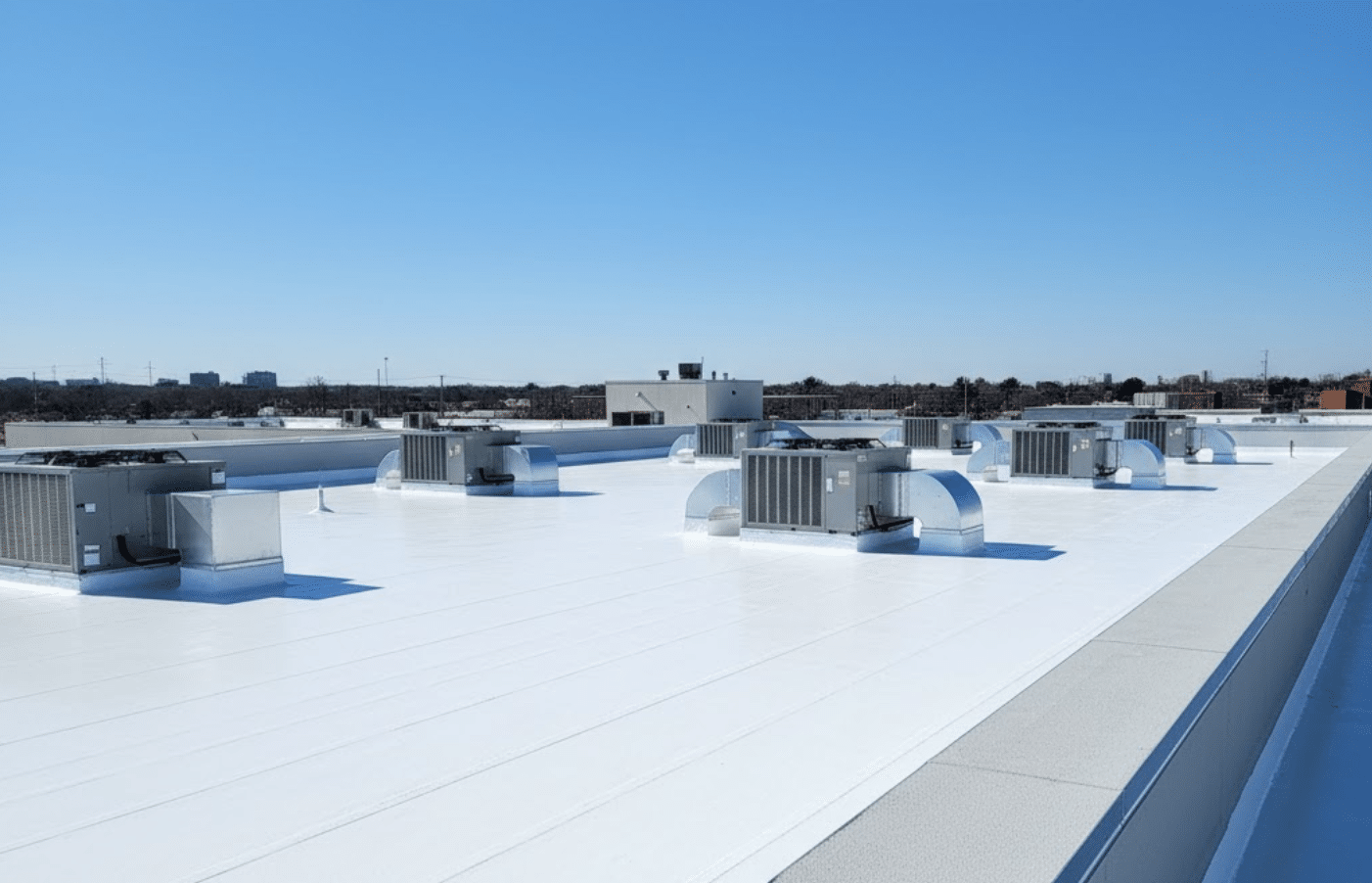 large commercial building rooftop under bright sky, representing the importance of knowing the commercial roof replacement cost